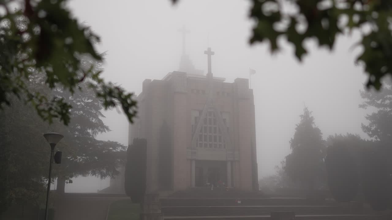 Church facade barely visible in thick morning fog at Santuário da Penha in Guimarães Portugal
