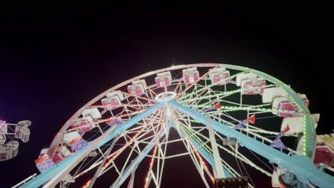 Looking-up-at-a-fully-lit-ferris-wheel-against-a-dark-night-sky