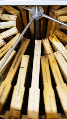 honey frames are stacked closely to each other in a metal barrel. the centrifuge device being rotated to extract honey. vertical video