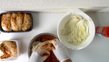 manos masculinas con guantes preparando kimchi coreano casero en la cocina
