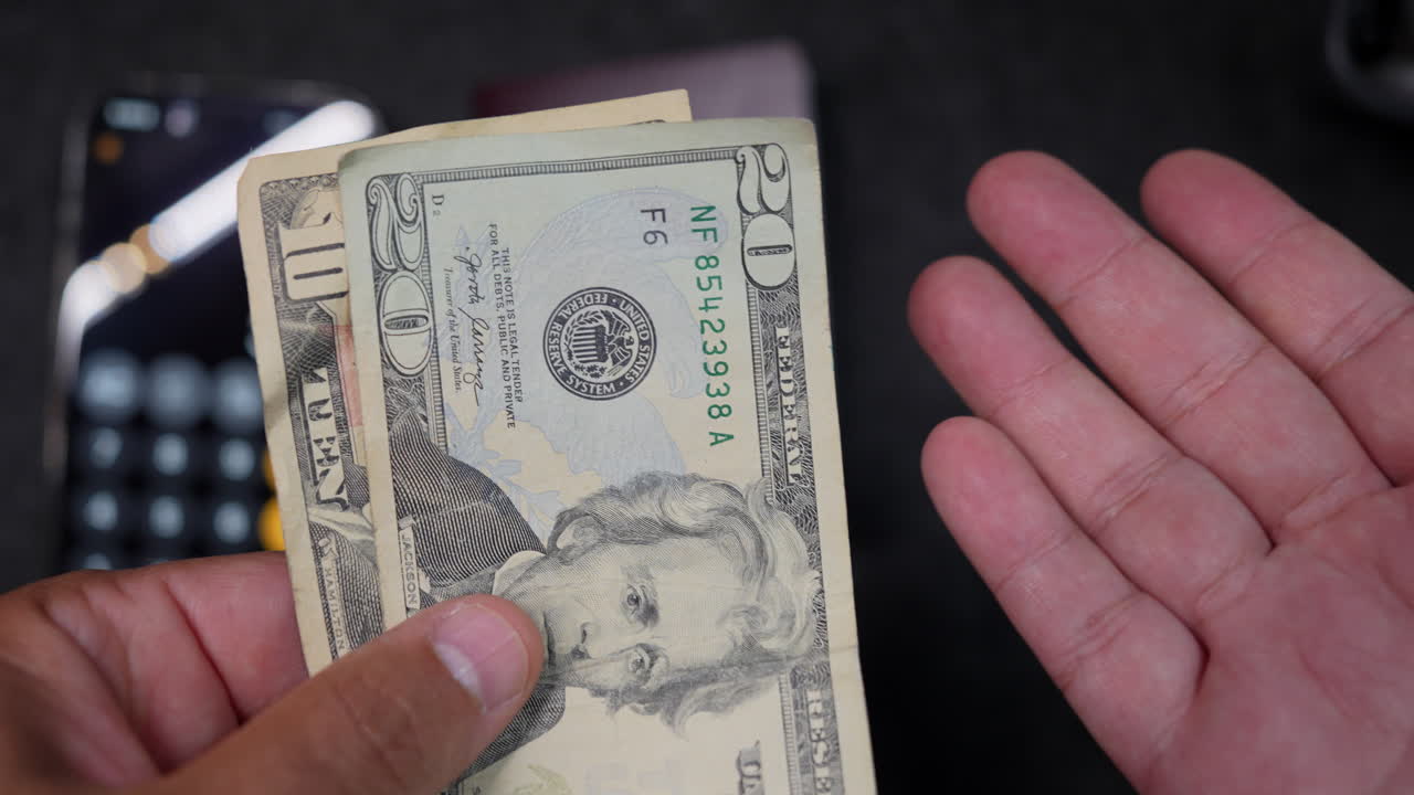 Close-up shot of hands counting crisp US dollar bills, focusing on the texture and detail with soft lighting and a blurred background, evoking themes of finance and economy