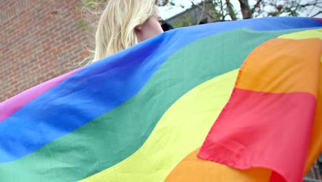 person holding up pride flag in wind