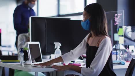 Mujer-Asiática-Con-Mascarilla-Limpiando-Su-Computadora-Portátil-Con-Pañuelos-En-La-Oficina-Moderna