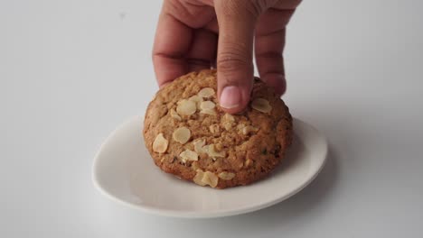 hand reaching for an oatmeal cookie on a white plate