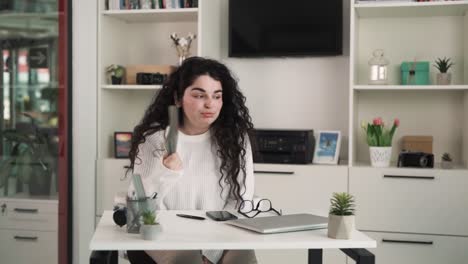 La-Niña-Está-Sentada-En-Una-Oficina-Sin-Aire-Acondicionado-Y-Muestra-Que-Tiene-Calor,-Agita-Un-Cuaderno-Frente-A-Ella-Para-Refrescarse