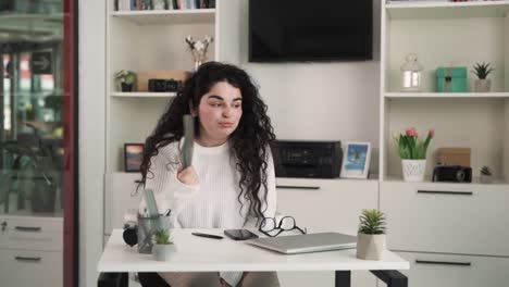 la chica está sentada en una oficina sin aire acondicionado y mostrando que está caliente, está agitando un cuaderno delante de ella para refrescarse