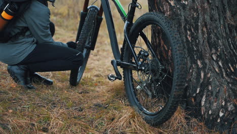 Ciclista-Masculino-Arreglando-Una-Bicicleta-De-Montaña-En-El-Campo