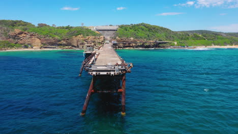 cormorant drying wing feathers on old australian disused pier, aerial arc shot