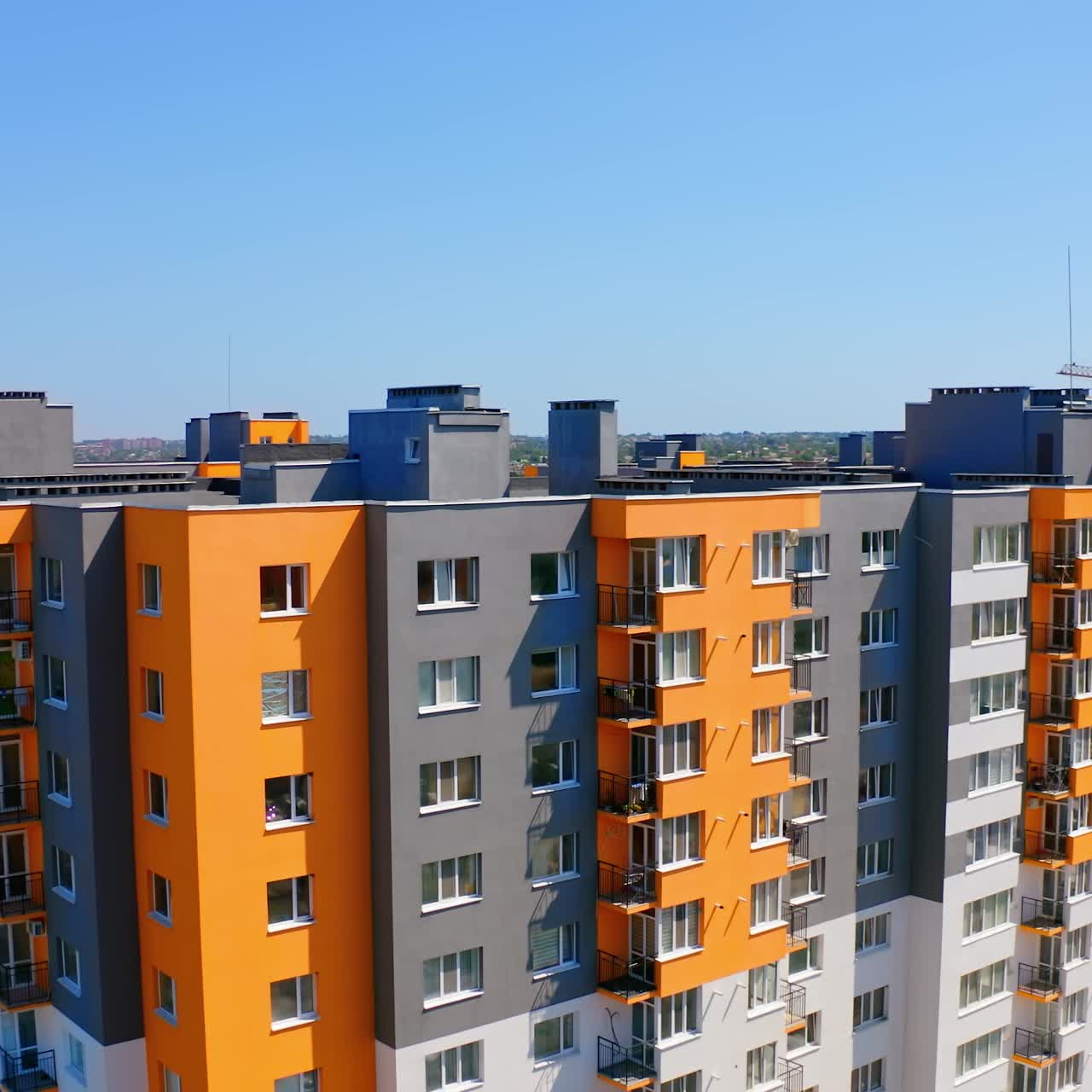 Bright multi-storey building in sunny day. Modern design of high-rise apartment building in the city. Exterior of new block of flats for residents under blue sky