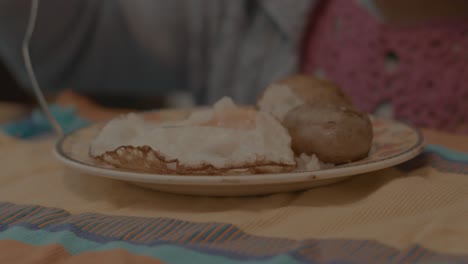 toma en cámara lenta de un plato de huevos y papas colocado frente a un niño