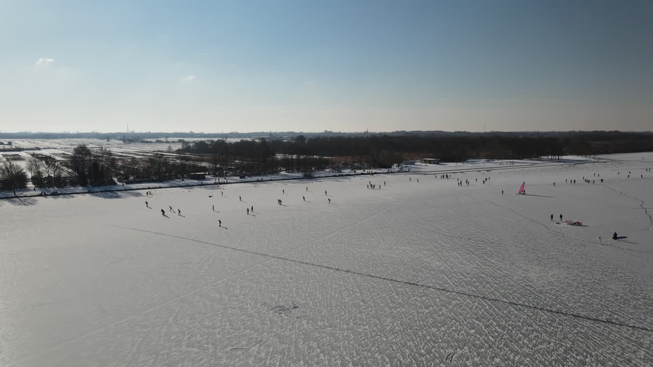 네덜란드에서 햇빛이 비치는 동안 얼어붙은 호수에서 사람들을 노는 아름다운 눈 덮인 풍경의 공중 촬영