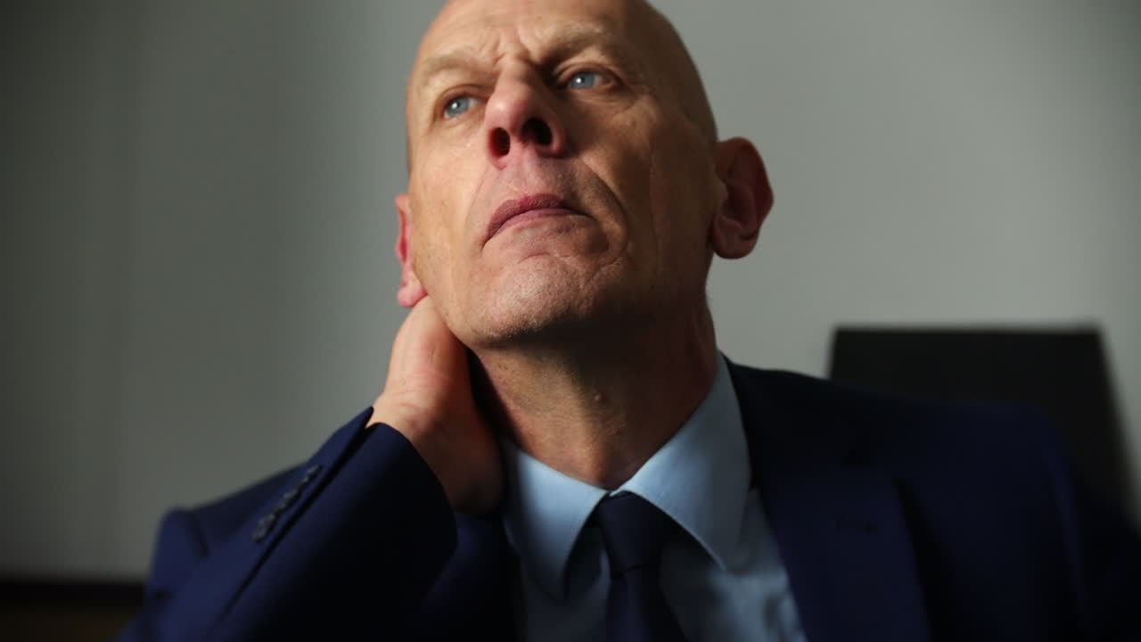 En stresset moden forretningsmand sidder i et mørkt rum.