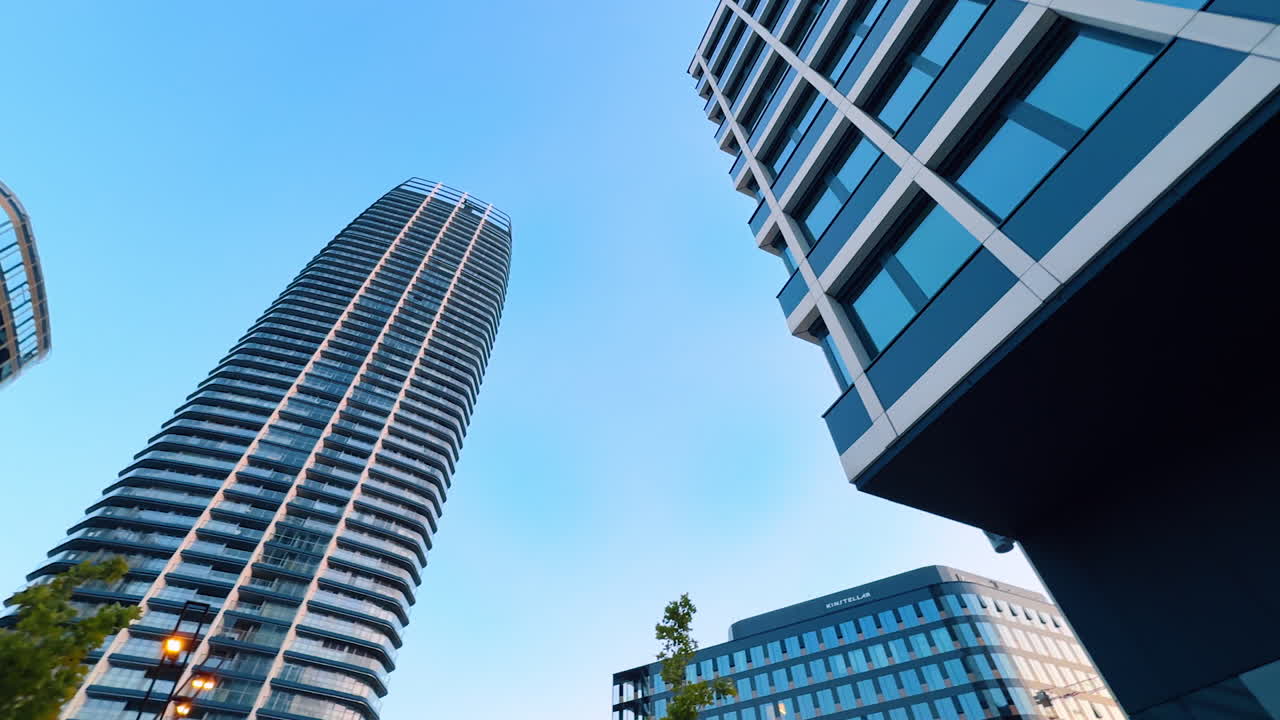 Modern architecture against a blue sky. Two modern buildings shine under a blue sky, featuring sleek lines and reflective glass panels