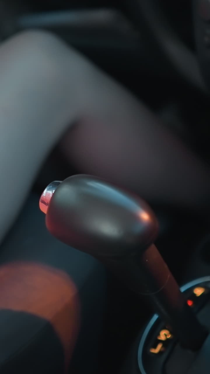 mujer en vestido rosa y corto sentado en su coche alcanza una taza de café cerca del cambio de marchas, el interior del coche es ligeramente borroso, con sombras de coches que pasan reflejando en ella