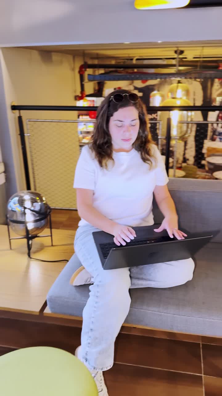 Ung kvindelig studerende begynder at arbejde på bærbar computer i en coworking-lobby.