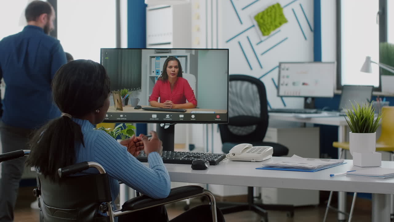 Manager sitting immobilized in wheelchair talking with partner on video call