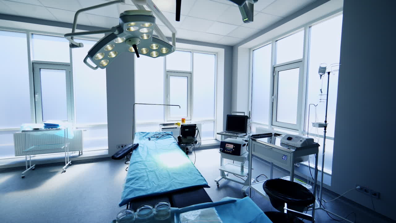 Empty new white operational room with big windows. Special apparatuses prepared for operation near the surgical table.