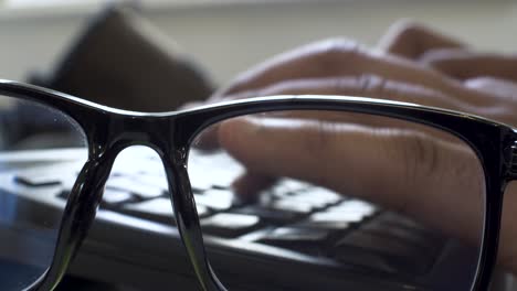 glasses with blue filter and typing on keyboard in closeup