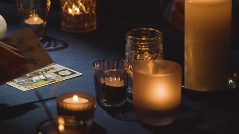 primer plano de una mujer dando una lectura de cartas de tarot a un hombre en la mesa 1 a la luz de las velas