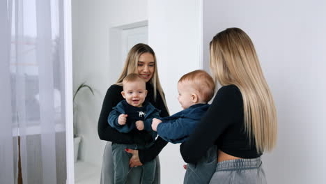 young blonde woman with long hair holds her cute child. mother and baby stand in front of a mirror.