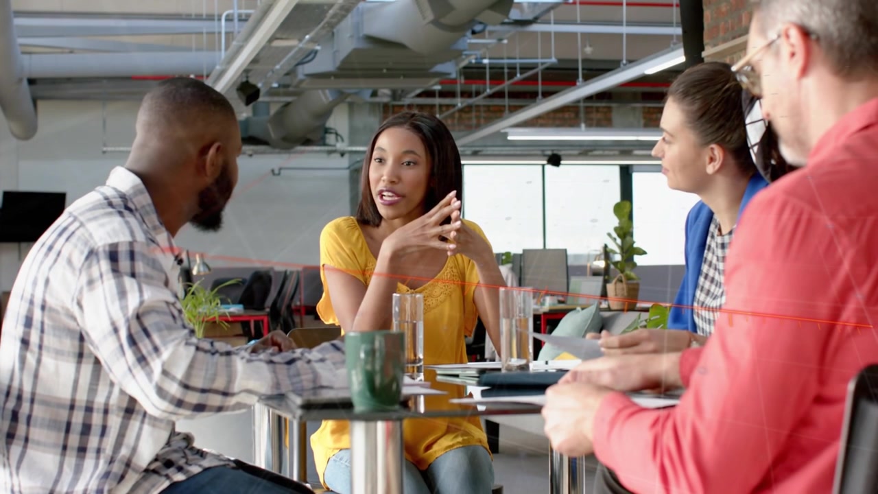 Woman in yellow starting conversation, gesturing, leading project discussion at round glass table