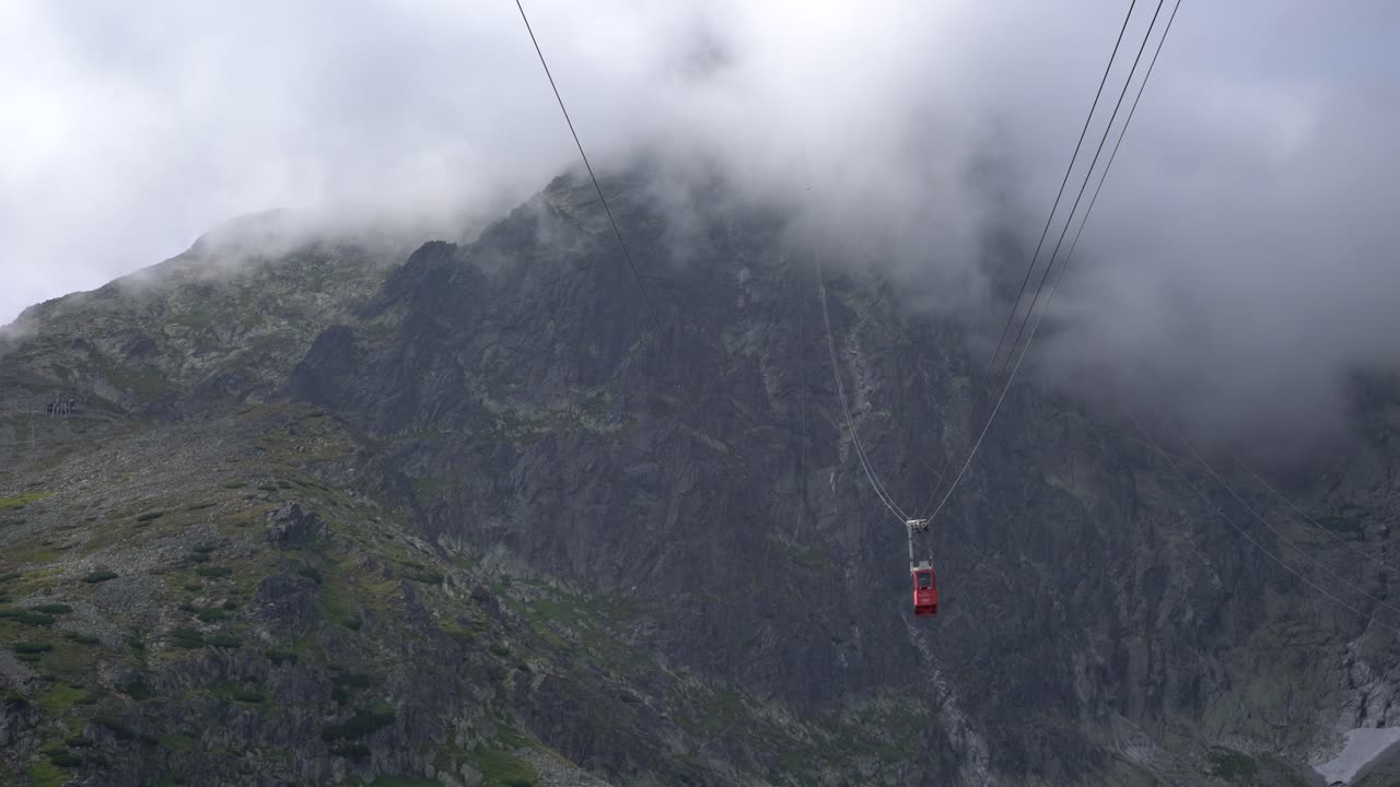 작은 빨간 곤돌라가 산봉우리 사이를 천천히 구름 속으로 지나간다