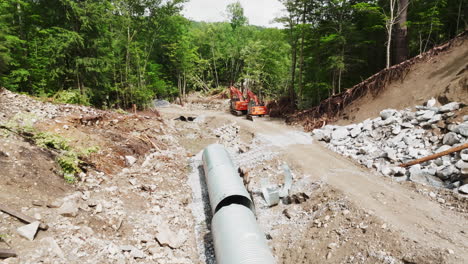 drone shot: construction site showing half-built concrete culvert and heavy excavation machinery