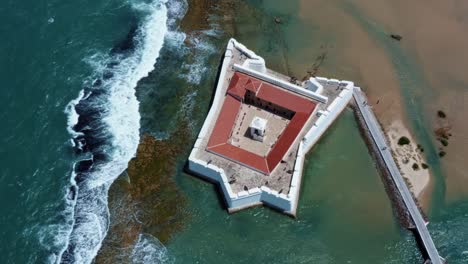 tilting up aerial drone shot of the historic star shaped reis magos fort built on a reef revealing the coastal capital city of natal in rio grande do norte, brazil in the background