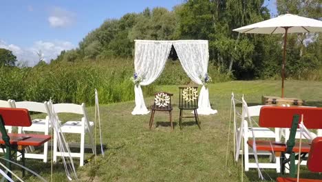 Increíble-Vuelo-Aéreo-De-Drones-De-La-Caminata-A-La-Boda-Imágenes-De-Una-Perfecta-Ubicación-De-Boda-Gratis-Frente-A-Asientos-Vacíos-En-La-Naturaleza-Junto-Al-Lago-En-Verano