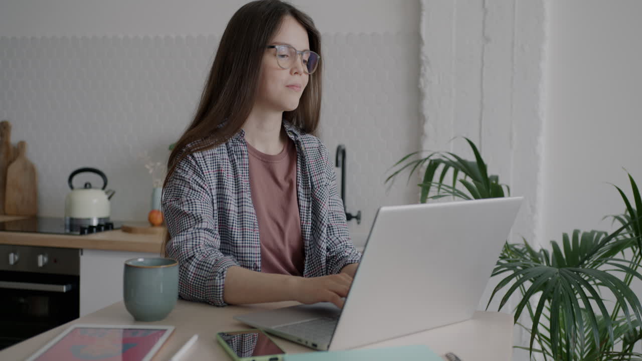 Young Woman Working on Laptop in a Kitchen