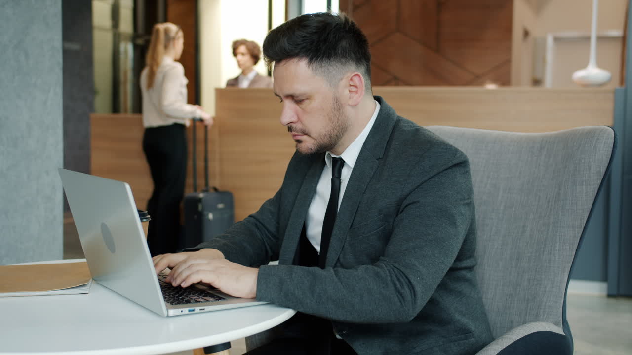 Businessman working on laptop in hotel lobby
