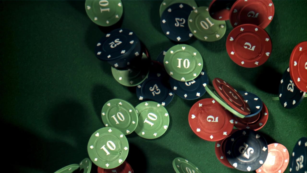 Fiches da casinò che cadono e si disperdono su un tavolo di feltro verde