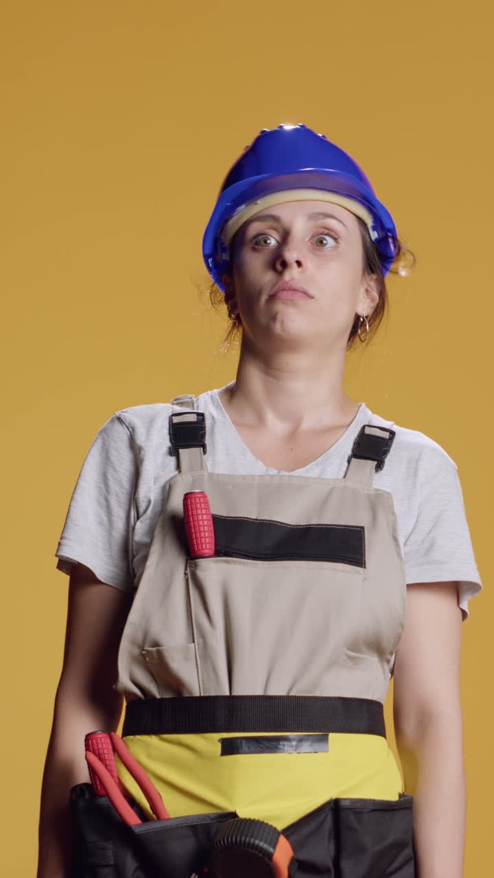 Vertical video: Portrait of female builder being hit in head and feeling dizzy