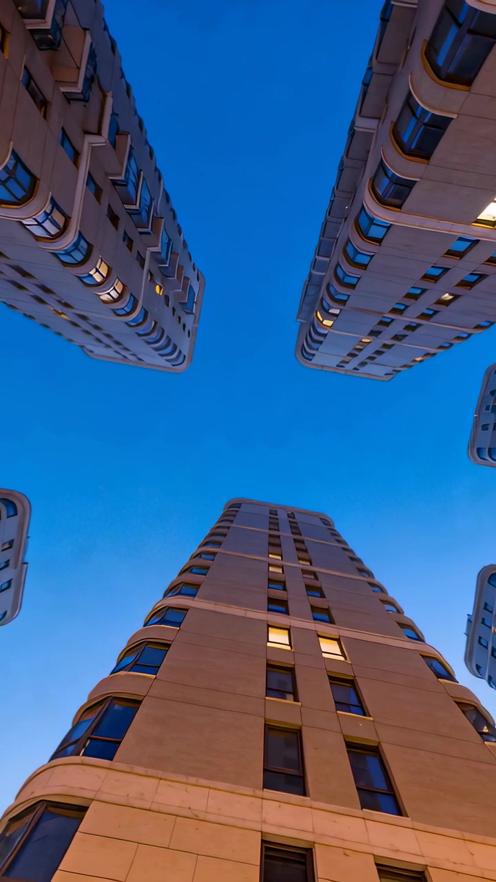 Video vertical: Cámara inclinándose, encuadrando una torre central en un hueco al anochecer, documentando la perspectiva.