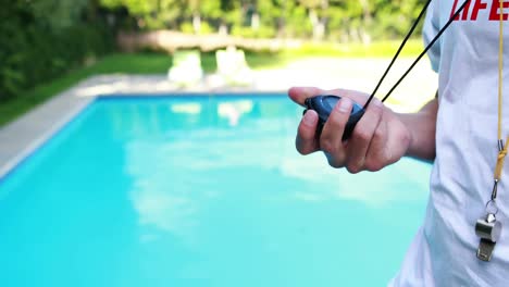 Lifeguard-looking-at-stopwatch-near-the-poolside