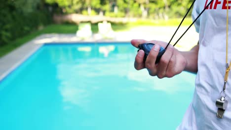 lifeguard looking at stopwatch near the poolside