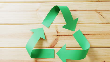 cierre de la basura y el símbolo de reciclaje de flechas de papel verde sobre fondo de madera