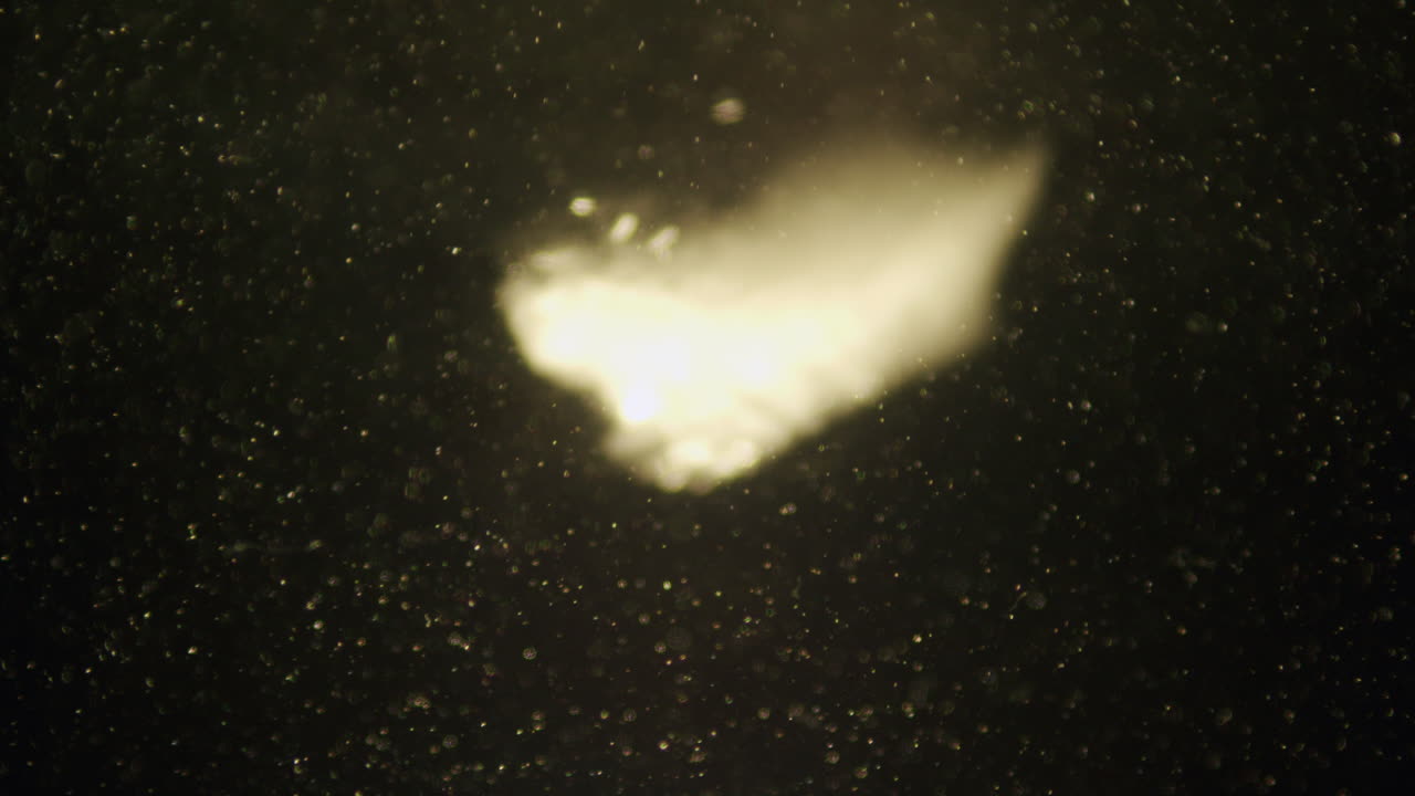 Ice cube falling in water in slow motion.