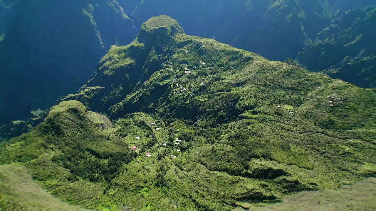 drone vuela lentamente sobre casitas en el enorme cráter del cirque du mafate en la isla francesa de la reunión