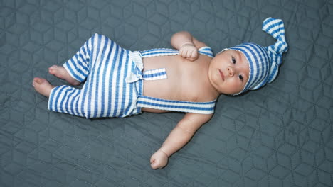nice child in a funny costume of a gnome. infant in a striped suit at the grey background. view from above.
