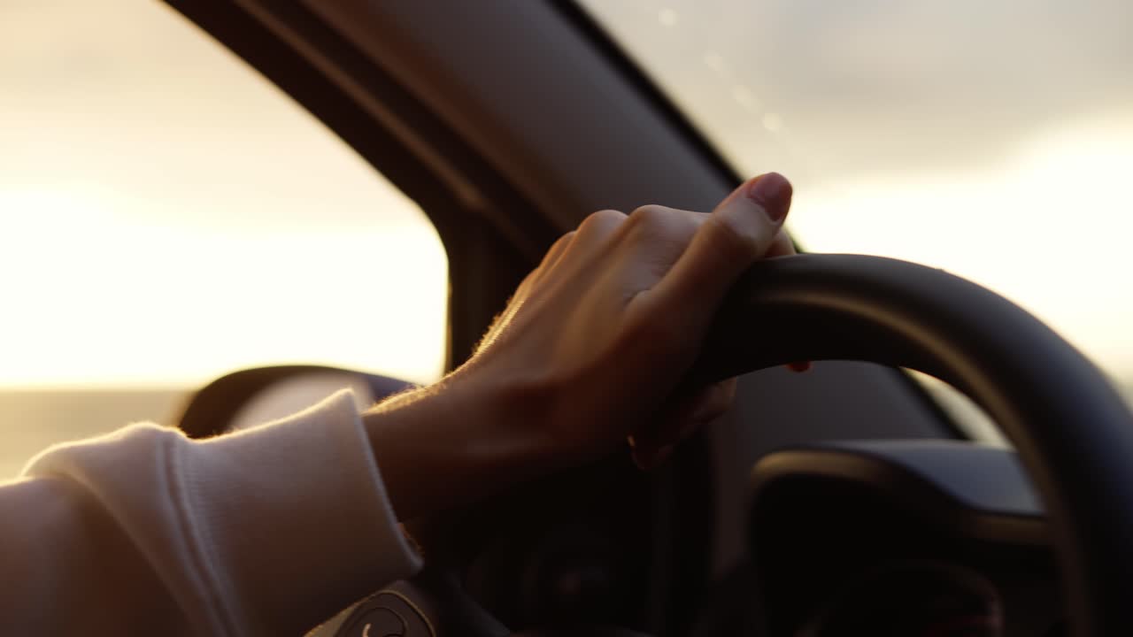 imágenes de cerca de una mujer con manicura desnuda conduciendo un coche a lo largo de la costa