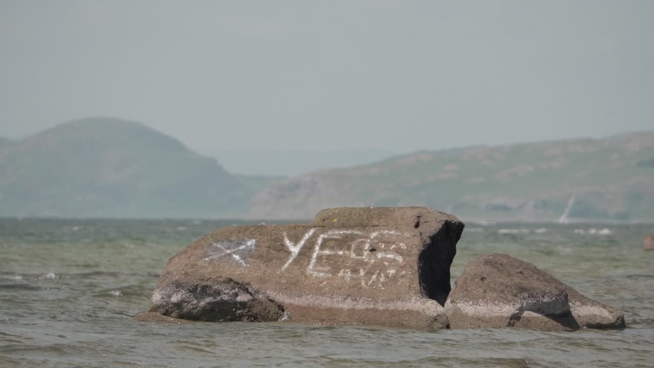 Scottish identity, rock painted ideology, ocean water, slow motion scene