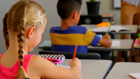 happy blonde caucasian schoolgirl studying at desk in classroom at school 4k