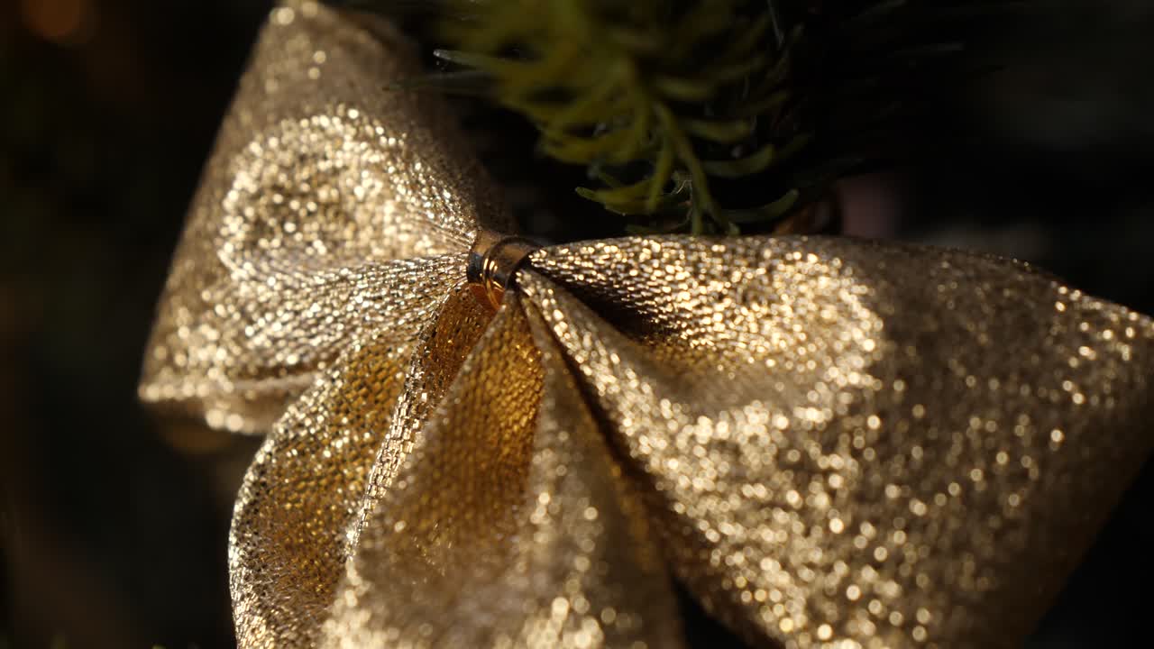 Enfeite de Natal dourado, cintilante e reluzente com nó, em plano detalhe deslizante.