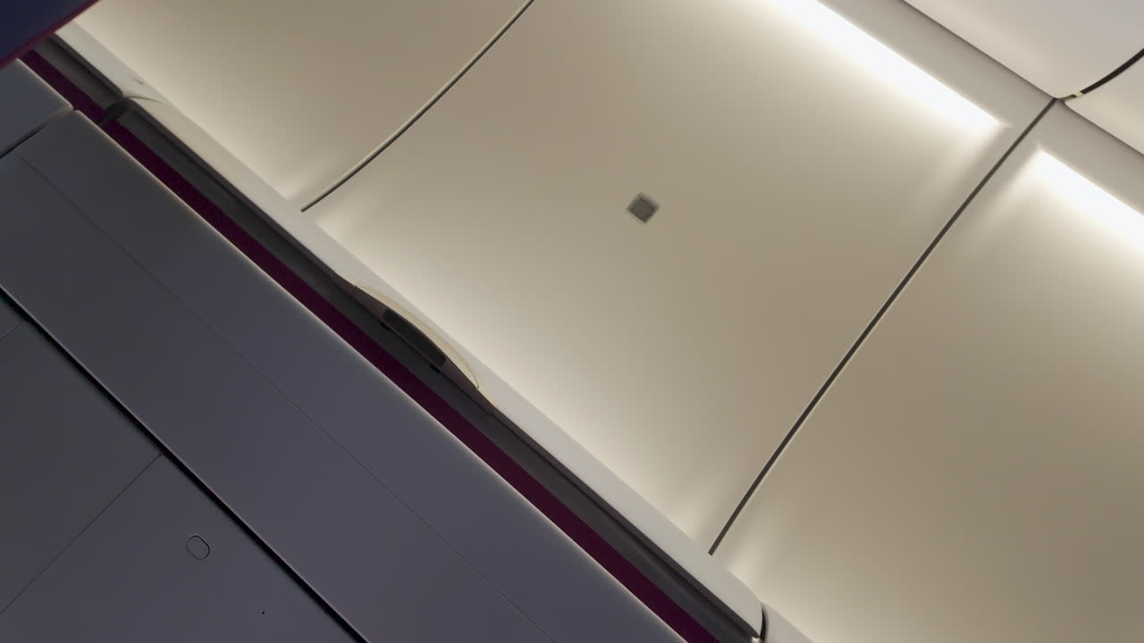 interior de un avión, específicamente el área del techo cerca de la entrada o la salida