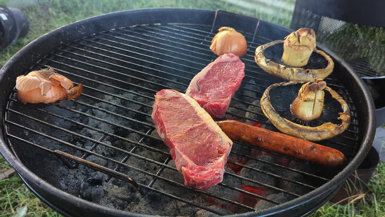 Man places a juicy steak on the bbq over hot coals with Aussie garden in background.