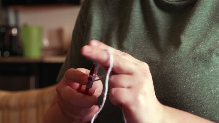 Close up of a caucasian woman doing a cast on stitch for knitting