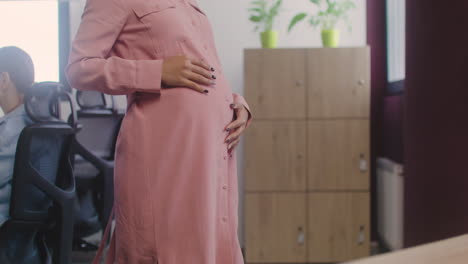 close up of happy pregnant woman with wirless earphones listening music and dancing in the office