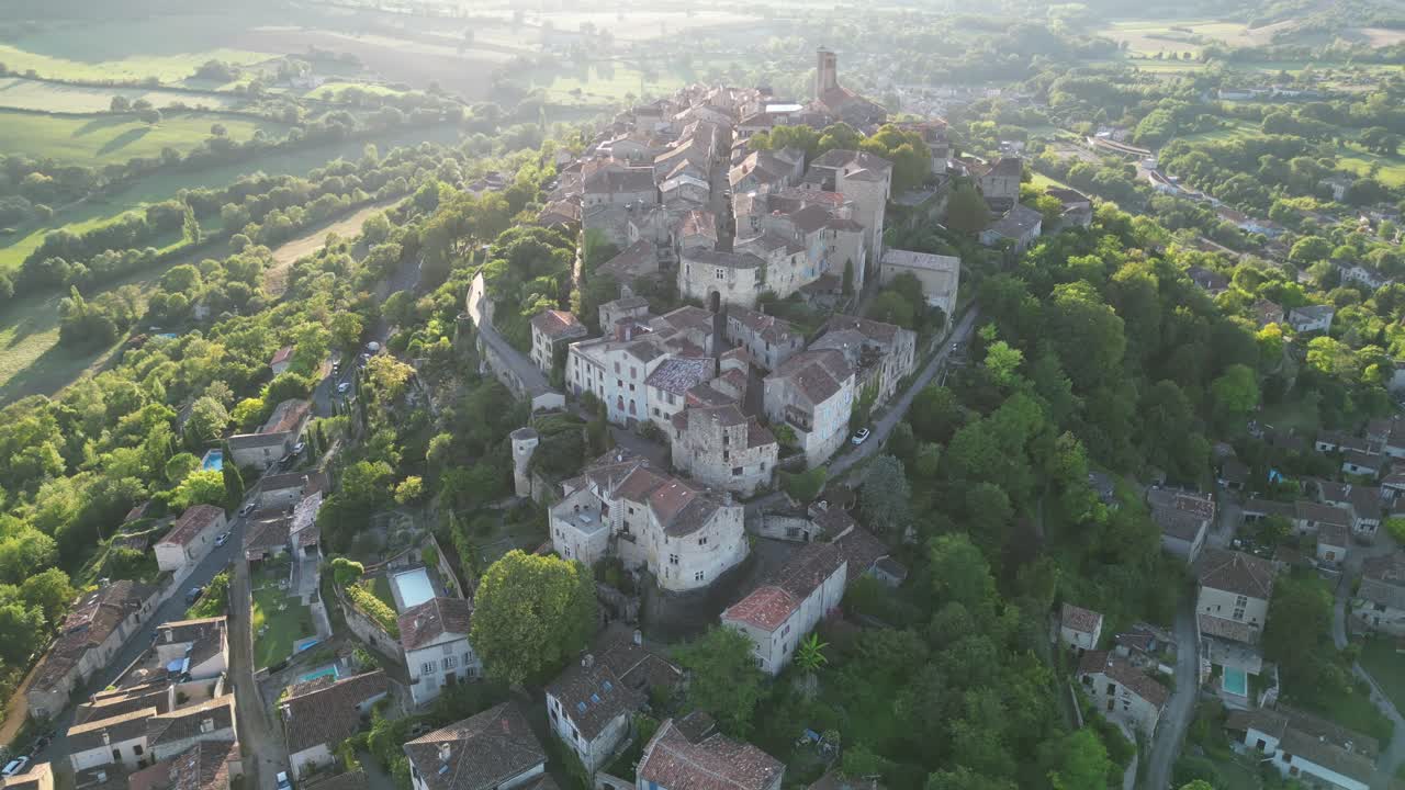 Drone aerial view in France countryside small old medieval brick town on a mountain top surrounded by green fields vertical ascend on a sunny day in Cordes Sur Ciel