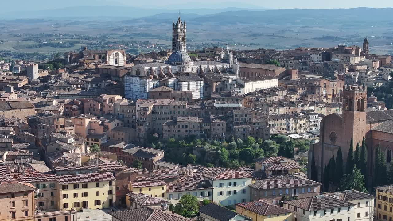 the magnificent Siena Cathedral (Duomo di Siena) and the densely packed medieval cityscape with traditional terracotta-tiled buildings, set against the backdrop of the rolling Tuscan countryside